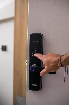 a person pressing a remote control on a wall at My Little Tiny House in Rhodes Town