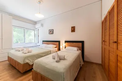 two beds in a room with white walls and wooden floors at My Green Eden in Rhodes in Ialyssos