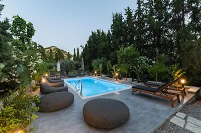 a swimming pool in a backyard with benches and aitating at My Green Eden in Rhodes in Ialyssos
