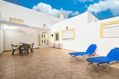 a patio with blue chairs and a table in a building at Sofia Traditional House in Afantou