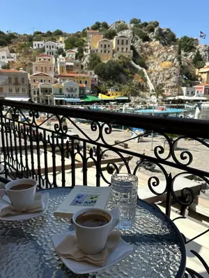 a table with two cups of coffee on a balcony at Amorosa House in Symi
