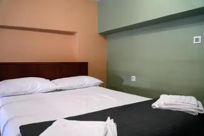 a bedroom with two beds with white sheets and a green wall at Symi Central Point in Symi