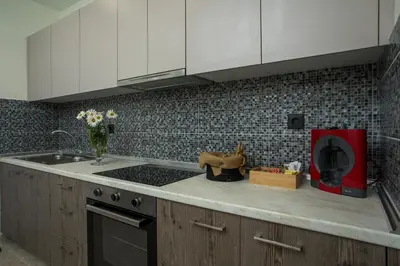 a kitchen with white cabinets and a stove top oven at Matsi Suites in Faliraki