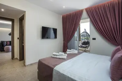 a bedroom with a bed with red curtains and a television at Matsi Suites in Faliraki