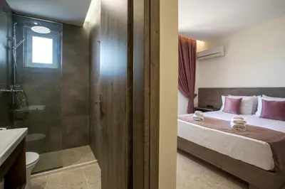 a bedroom with a bed and a shower and a bathroom at Matsi Suites in Faliraki