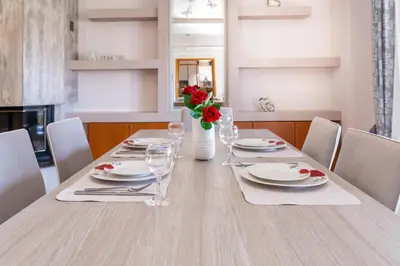 a dining room table with white plates and red roses at Casa della Pace in Ialyssos