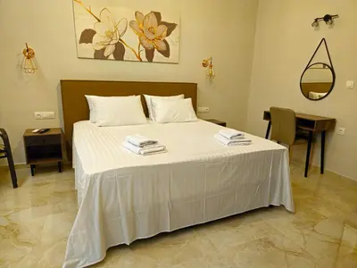 a bedroom with a bed with white sheets and a table at Nereides Apartments Rhodes in Kremasti