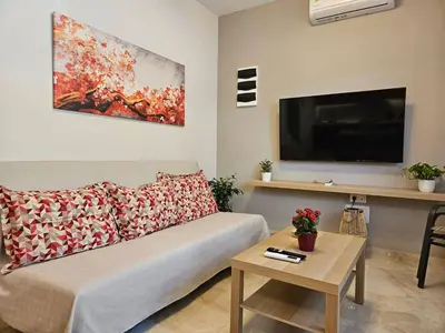 a living room with a couch and a flat screen tv at Nereides Apartments Rhodes in Kremasti