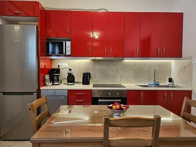 a kitchen with red cabinets and a table with chairs at Nereides Apartments Rhodes in Kremasti