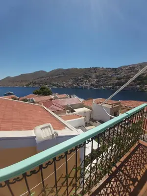 a balcony with a view of a city and the water at 89 Steps Symi in Symi