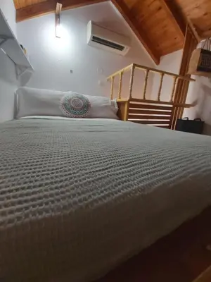 a large bed in a room with a ladder at 89 Steps Symi in Symi