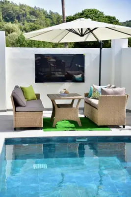 a patio with two chairs and an umbrella next to a pool at Melia Casa in Rhodes Town