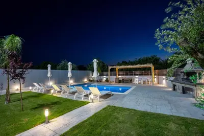 a backyard with a swimming pool at night at Villa Pasadra in Afantou