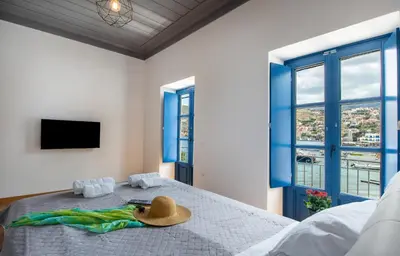 a hat on a bed in a room with windows at Porto Harani Seaside Apartments in Symi