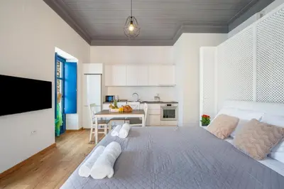 a bedroom with a large bed and a kitchen at Porto Harani Seaside Apartments in Symi