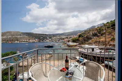 a table with a bottle of wine on a balcony at Porto Harani Seaside Apartments in Symi