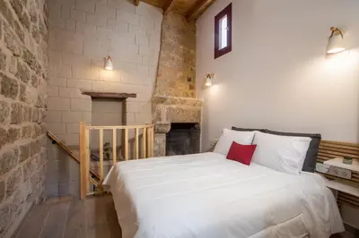 a bedroom with a white bed and a fireplace at Alexandras Stone House in Rhodes Town