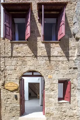 a stone building with pink doors and windows at Alexandras Stone House in Rhodes Town