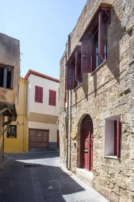 an alley in an old stone building with red doors at Alexandras Stone House in Rhodes Town