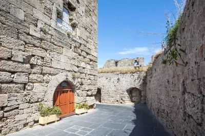 a stone building with a wooden door and a gate at Alexandras Stone House in Rhodes Town