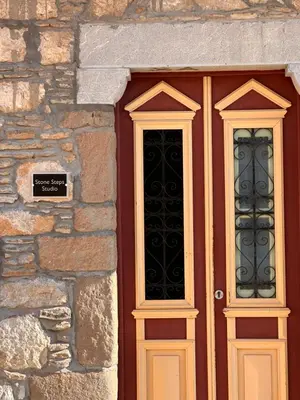 a wooden door with two windows on a stone building at Stone Steps Studio in Symi