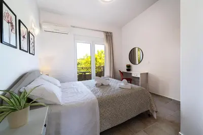 a white bedroom with a bed and a window at Shady Tree Villa in Ialyssos
