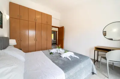 a bedroom with a large white bed with a desk and a desk at Shady Tree Villa in Ialyssos