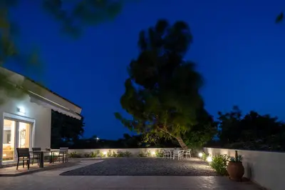 a patio with tables and chairs at night at Shady Tree Villa in Ialyssos