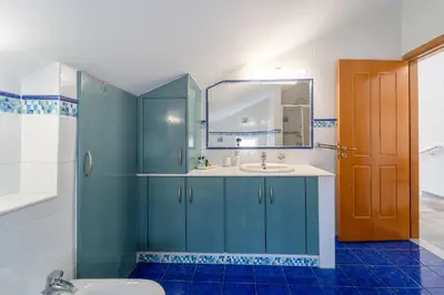 a blue bathroom with a sink and a mirror at Shady Tree Villa in Ialyssos