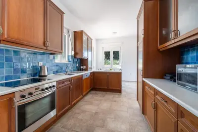 a large kitchen with wooden cabinets and blue tiles at Shady Tree Villa in Ialyssos