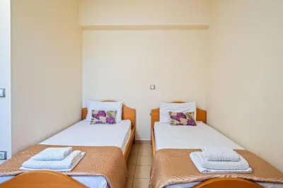 two twin beds in a room with white walls at Villa Victoria in Afantou
