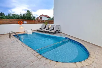 a swimming pool with chairs on a patio at Villa Victoria in Afantou