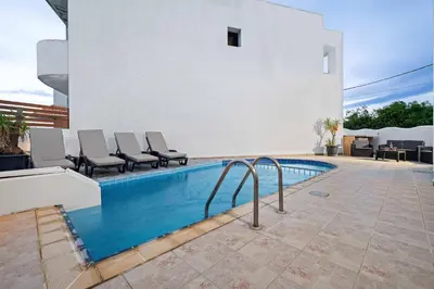 a swimming pool with chairs next to a house at Villa Victoria in Afantou