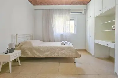 a white bedroom with a bed and a window at Ntina's Apartment in Rhodes Town