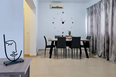 a dining room with a table and chairs and a clock at Ntina's Apartment in Rhodes Town