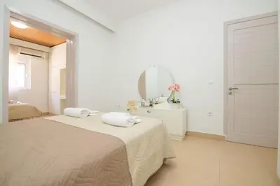 a white bedroom with a bed and a mirror at Ntina's Apartment in Rhodes Town