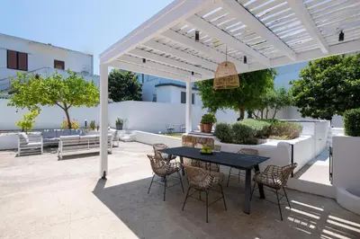 a patio with a black table and chairs under a white pergola at Villa Lou in Rhodes Town