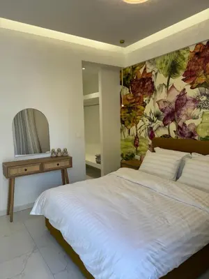 a bedroom with a large white bed with a painting on the wall at Cozy City Center Apartment B in Rhodes Town