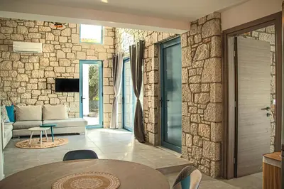 a living room with a stone wall at Anasa Rustic Villa in Kolimbia
