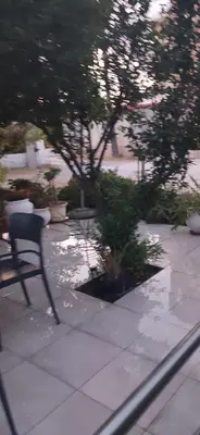 a chair sitting on a patio with trees and plants at Tsampikas House in Faliraki