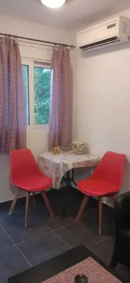 a room with two red chairs and a table and a window at Tsampikas House in Faliraki