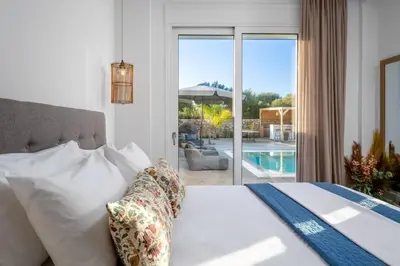 a bedroom with a bed and a view of a pool at Amora Pool Villas in Gennadi