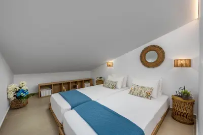 a bedroom with a large white bed with a blue blanket at Amora Pool Villas in Gennadi