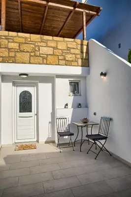 a patio with a table and chairs and a stone wall at Villa Chris - Malona in Malona Village