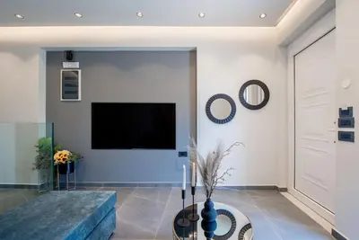 a living room with a couch and a tv on a wall at Santa Marina Luxury Apartments #1 with pool in Asgourou