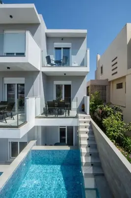 a building with a swimming pool in front of a house at Santa Marina Luxury Apartments #1 with pool in Asgourou
