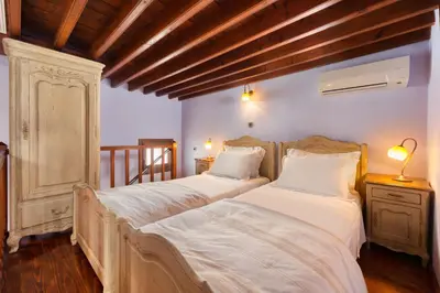 two beds in a room with wooden ceilings at Residenza Maria Lindos Villa in Líndos