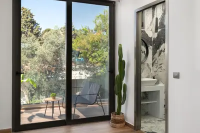 a sliding glass door with a chair and a cactus at La Siesta Villas in Ixia