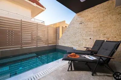 a pool with a chair next to a swimming pool at La Siesta Villas in Ixia