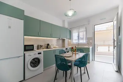 a kitchen with green cabinets and a table and chairs at Antonis Studio in Archangelos